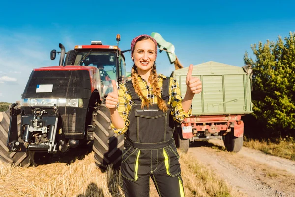 Agricoltore donna di fronte a macchine agricole dando pollice in su — Foto Stock