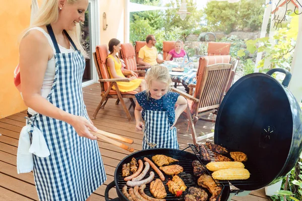 Barbeque party in the garden with mom and her daughter at the grill — Stock Photo, Image