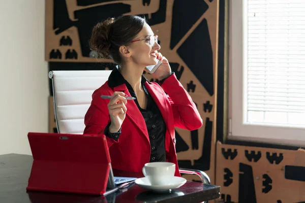Bizneswoman w swoim biurze siedzi przy biurku z telefonem — Zdjęcie stockowe