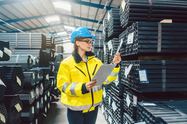 Arbeiterin überprüft Inventar in einem Stahllager — Stockfoto