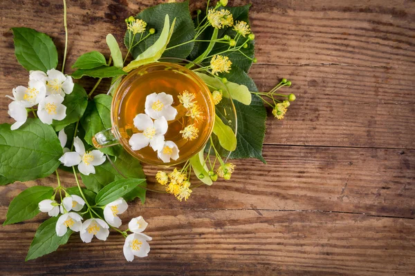 Herbal tea with jasmine and linden flowers on rustic table — Stock Photo, Image