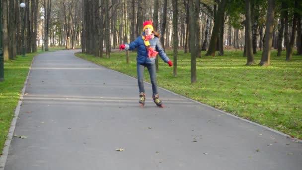 Lachende meisje ritje in herfst park op rollerblades — Stockvideo