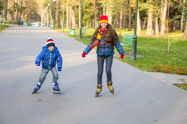 İki çocuk sonbahar parkta paten üzerinde binmek için öğrenme — Stok fotoğraf