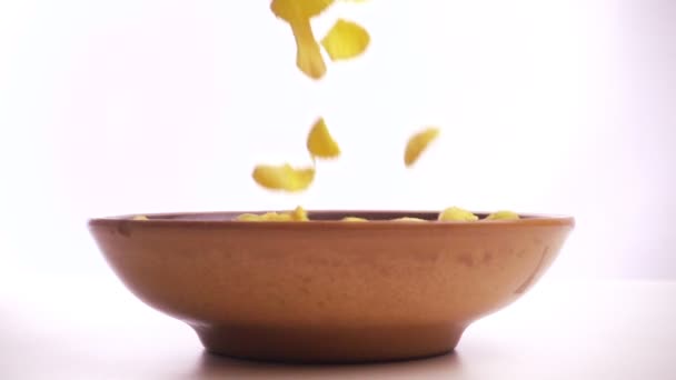 Cornflakes vallen in de kom op witte achtergrond, slow-motion — Stockvideo