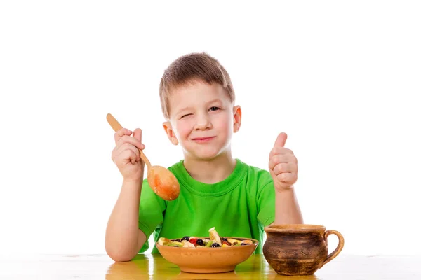 Funny boy eating oatmeal at the table — Stock Photo, Image
