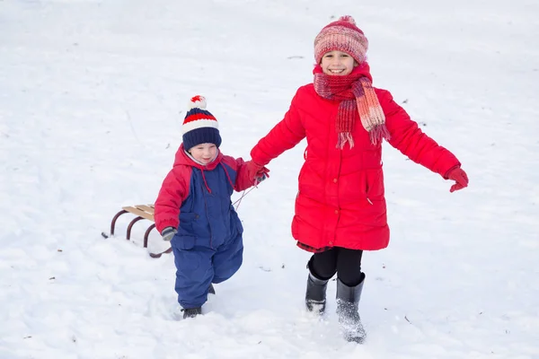 Two happy kids with sled walking on snow — Stock Photo, Image