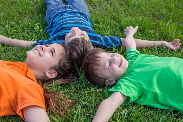 Yeşil çimenlerin üzerinde uzanmış üç rüya çocuk — Stok fotoğraf