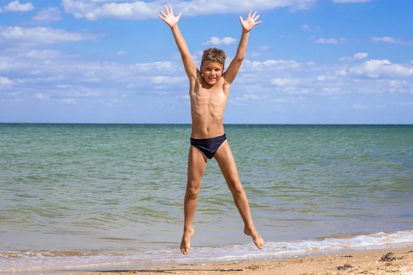 Pojke hoppar på stranden — Stockfoto