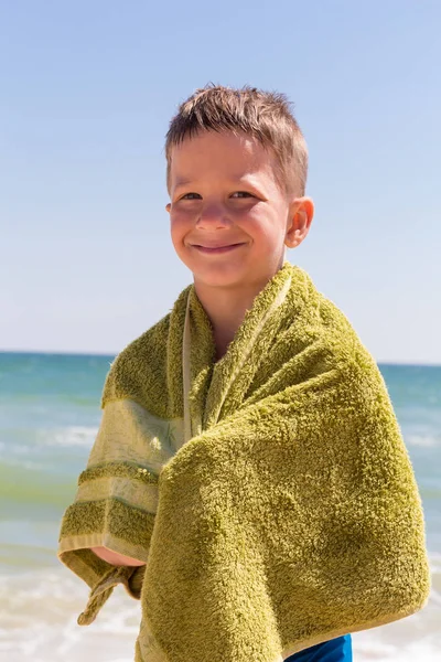 Smilende gutt i håndkleet på stranden – stockfoto