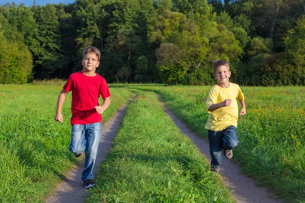Dos chicos felices corriendo juntos en el camino de campo —  Fotos de Stock