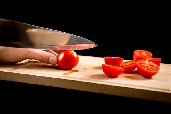 Cutting red cherry tomatoes on wooden board — Stock Photo, Image
