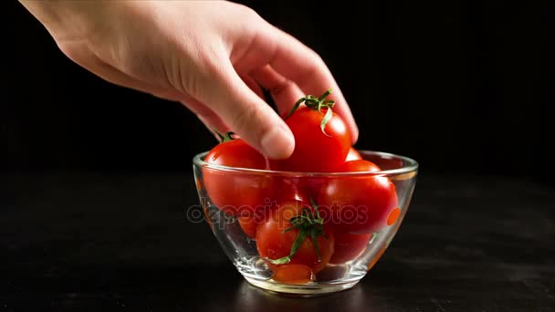 Recogiendo un tomate cherry de un tazón de vidrio — Vídeo de stock