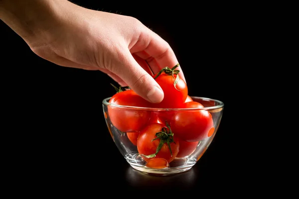 Picking up one cherry tomato from glass bowl — Stock Photo, Image