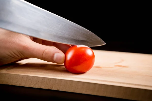 Cutting little red cherry tomato on wooden board — Stock Photo, Image