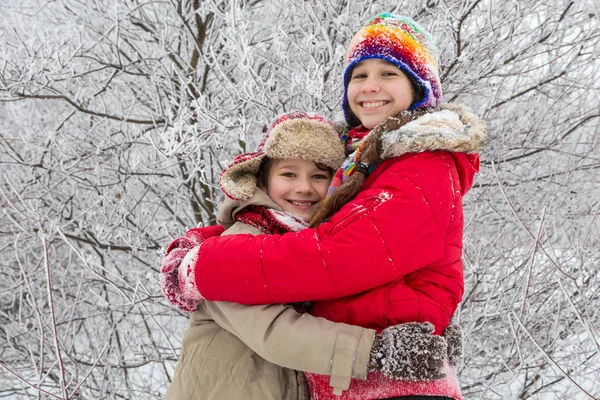 Dvě děti objímat společně na zimní les — Stock fotografie