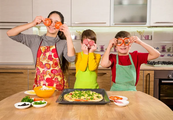 Três miúdos engraçados a fazer a pizza — Fotografia de Stock