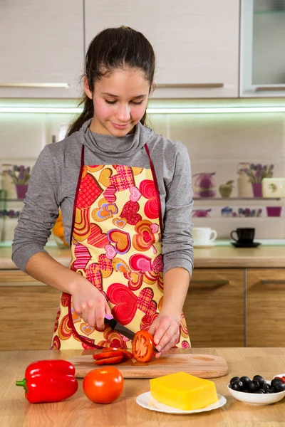 Очаровательная молодая девушка режет помидоры на кухне — стоковое фото
