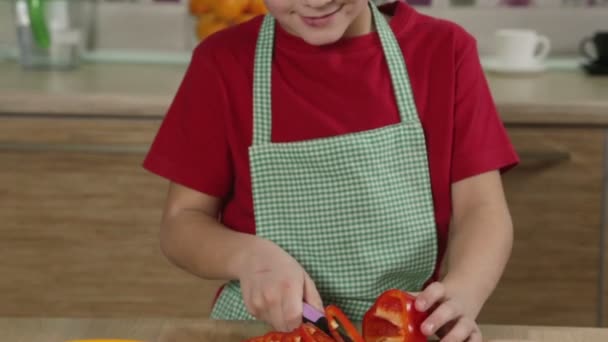 Schattige jongen snij de paprika in keuken — Stockvideo