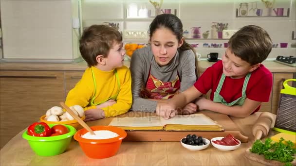 Трое детей читают поваренную книгу, готовят ужин — стоковое видео