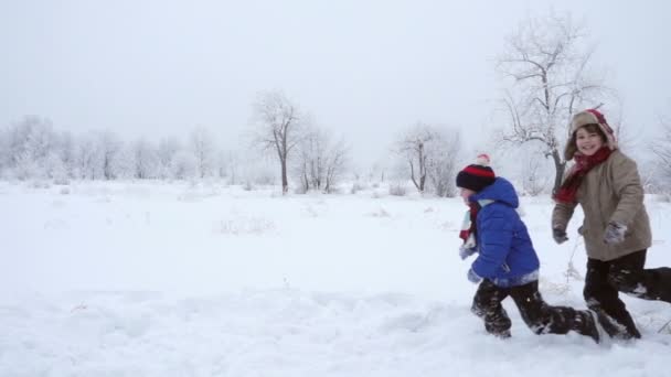 Трое детей бегают вместе по зимнему пейзажу, замедленная съемка — стоковое видео