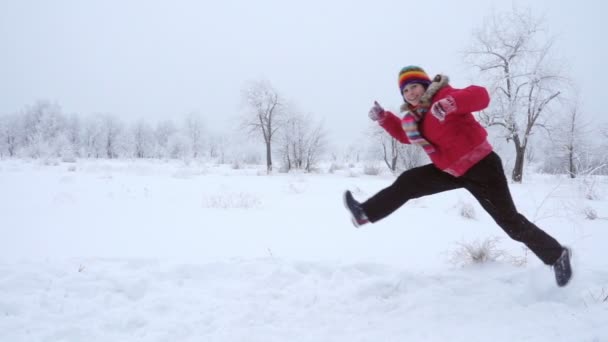 Девушка бегает и прыгает по зимнему пейзажу, замедленная съемка — стоковое видео