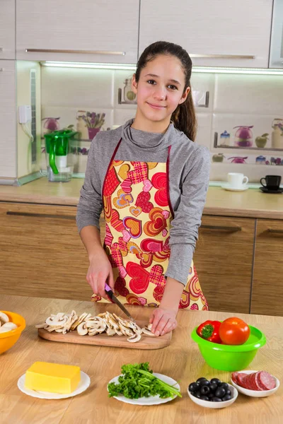 Очаровательная молодая девушка срезала грибы на кухне. — стоковое фото