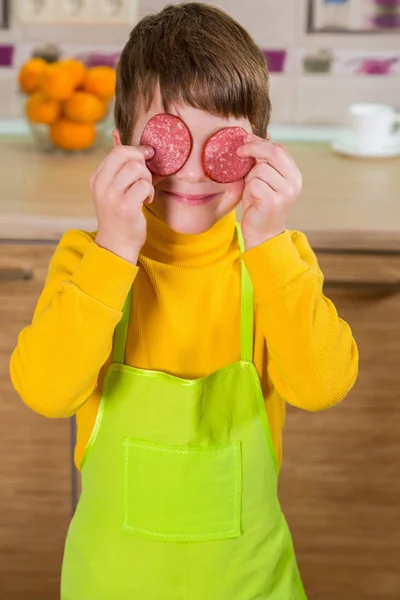 Смешной мальчик с нарезанной салями на глазах — стоковое фото