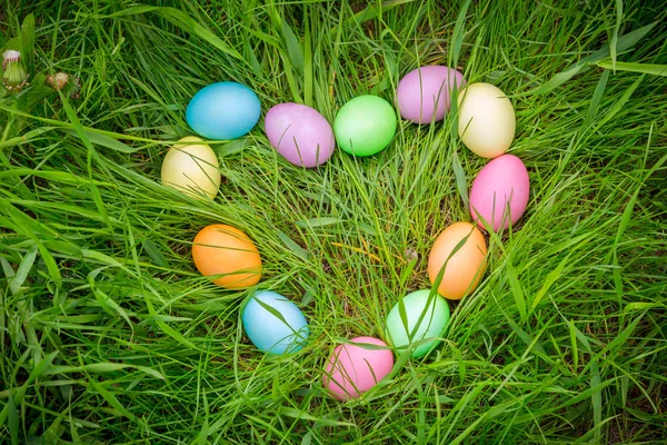 Fond avec des œufs de Pâques colorés sur la pelouse en forme de coeur — Photo