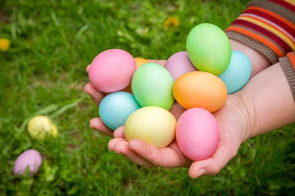 Ovos de páscoa coloridos em mãos no gramado verde — Fotografia de Stock