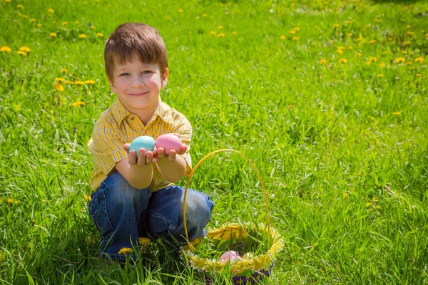小男孩与彩色复活节鸡蛋在绿色的草坪上 — 图库照片