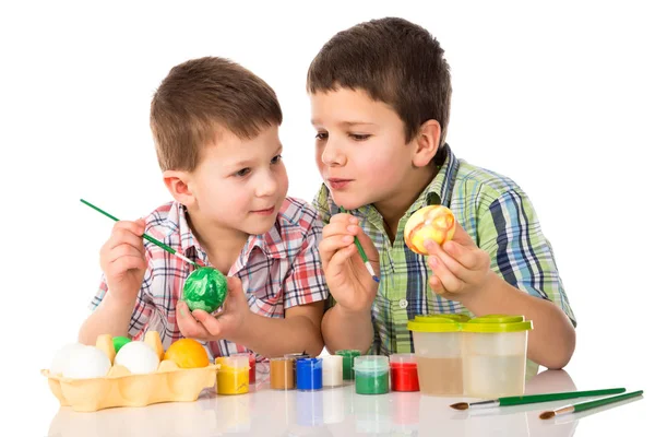 Twee lachende kinderen schilderen paaseieren samen aan tafel — Stockfoto