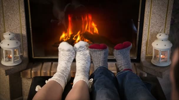 Las piernas de la pareja en calcetines de lana se calientan cerca de la chimenea — Vídeos de Stock