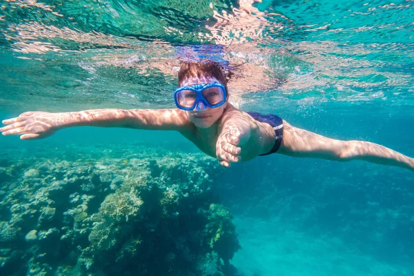 Jongen in zwemmen masker duik in de rode zee in de buurt van coral reef — Stockfoto