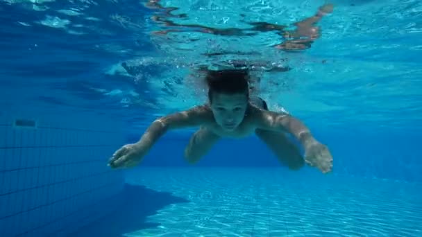 Мальчик в бассейне плавает под водой — стоковое видео