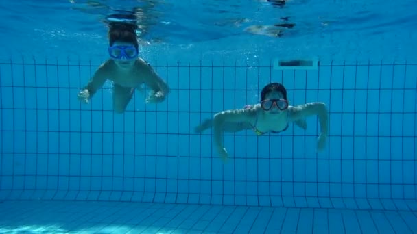 Boy and girl in swimming pool swim underwater — Stock Video