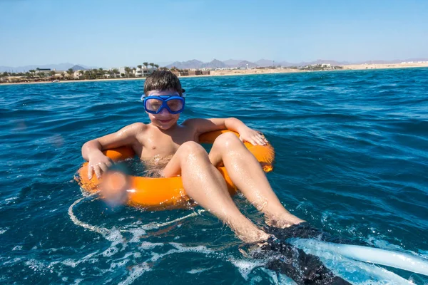 Lächelnder Junge schwimmt auf Rettungsring im Meer — Stockfoto