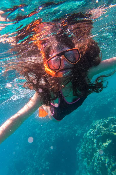 Meisje in zwemmen masker duiken in zee in de buurt van coral reef — Stockfoto