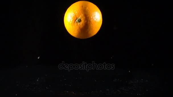 Frutta arancione cadente su sfondo nero, rallentatore — Video Stock