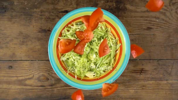 Falling cut tomato in dish with salad, slow motion — Stock Video