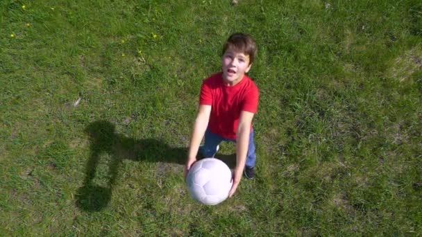 Boy hodí míč, stojící na zelené louce, pomalý pohyb — Stock video