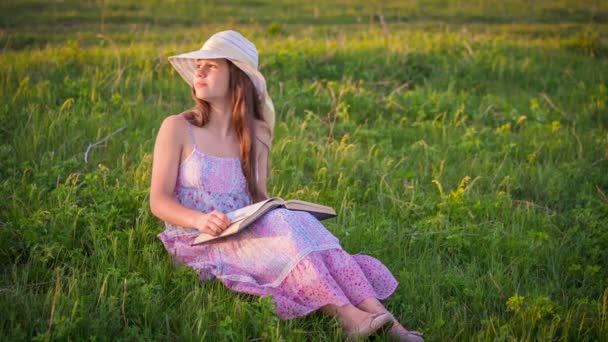Romantiska tjej läser boken på grön äng — Stockvideo