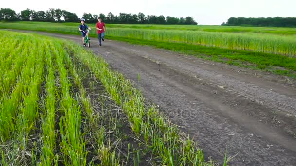 Dwoje dzieci uruchomiona wraz z rowerem na wiejski krajobraz — Wideo stockowe
