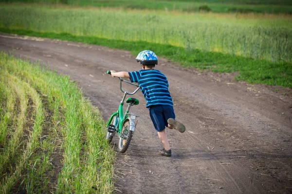 Mały chłopiec chodzenie pod górę z jego rower na wiejski krajobraz — Zdjęcie stockowe