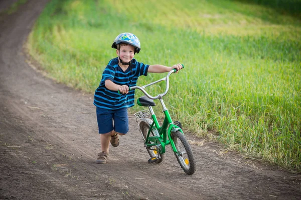 小男孩与他的自行车在农村景观上运行 — 图库照片