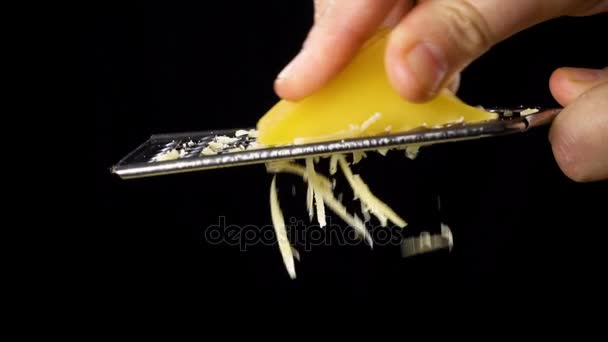 Hand bubbing the cheese on metal grater on black background — Stock Video