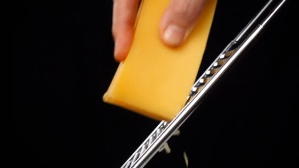 Esfregando o queijo em ralador de metal isolado em fundo preto — Vídeo de Stock