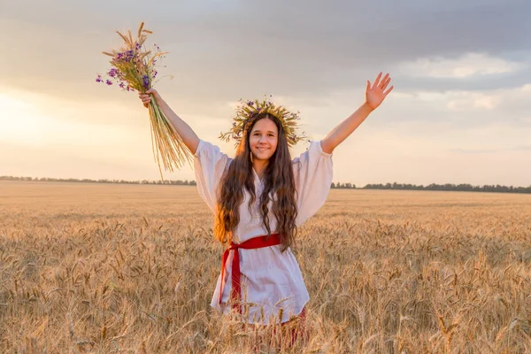 Girl walking with sheaf on wheat field at sunset, touching the e — Stock Photo, Image