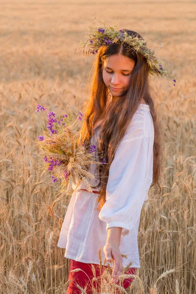 Girl walking with sheaf on wheat field at sunset, touching the e — Stock Photo, Image