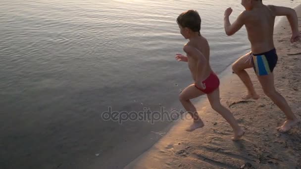 Τρία παιδιά που τρέχουν ποτάμι στο ηλιοβασίλεμα, αργή κίνηση — Αρχείο Βίντεο