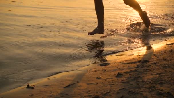 Sziluettjét két gyerek fut beach napnyugtakor — Stock videók